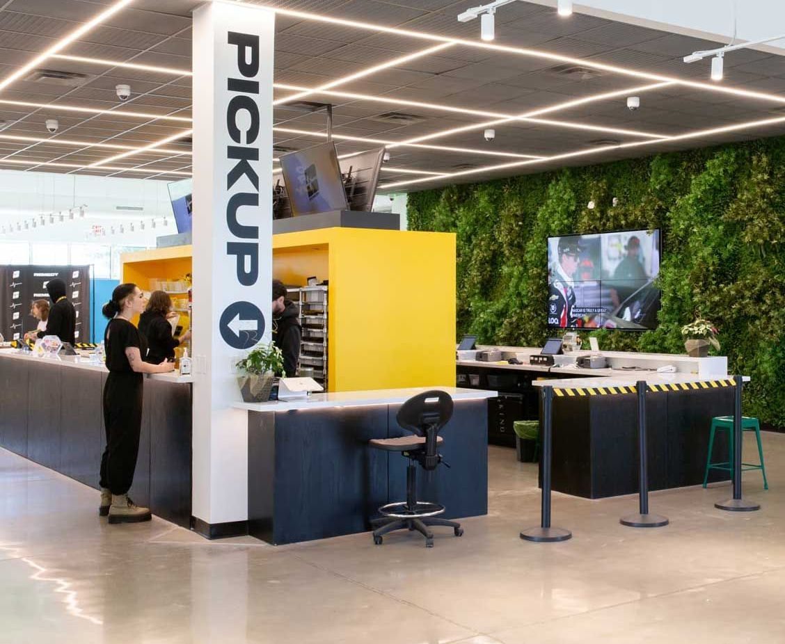 Bright dispensary interior with pickup counter and green living wall